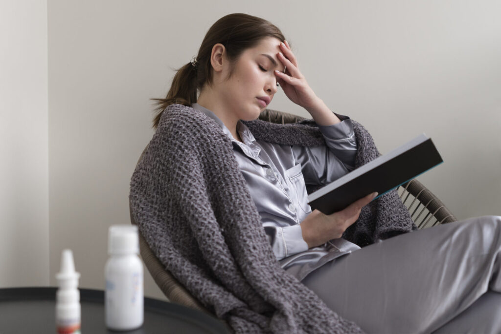 Mulher lendo livro com dor de cabeça e mal-estar