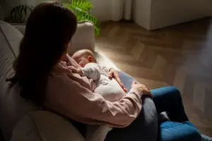 Mãe amamentando o bebê no sofá, representando os desafios emocionais da depressão pós-parto.