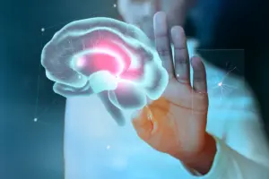 Mão de uma pessoa interagindo com uma projeção holográfica de um cérebro humano com áreas iluminadas em vermelho, simbolizando a atividade neurológica e os principais transtornos mentais na infância.