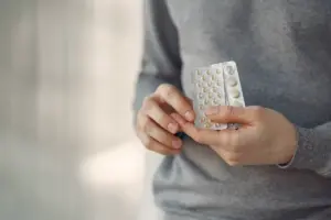 Pessoa segurando em close-up duas cartelas de medicamentos, representando os antidepressivos usados no tratamento de transtornos como depressão e ansiedade. O uso desses medicamentos tem como principal função a regulação de neurotransmissores no cérebro.
