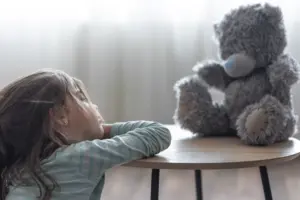 Ansiedade infantil representada por uma criança triste com um ursinho.